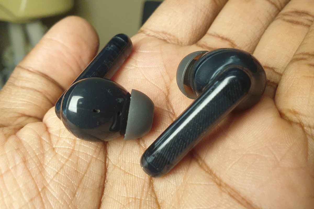 Man holding a pair of wireless earbuds: oraimo freepods lite