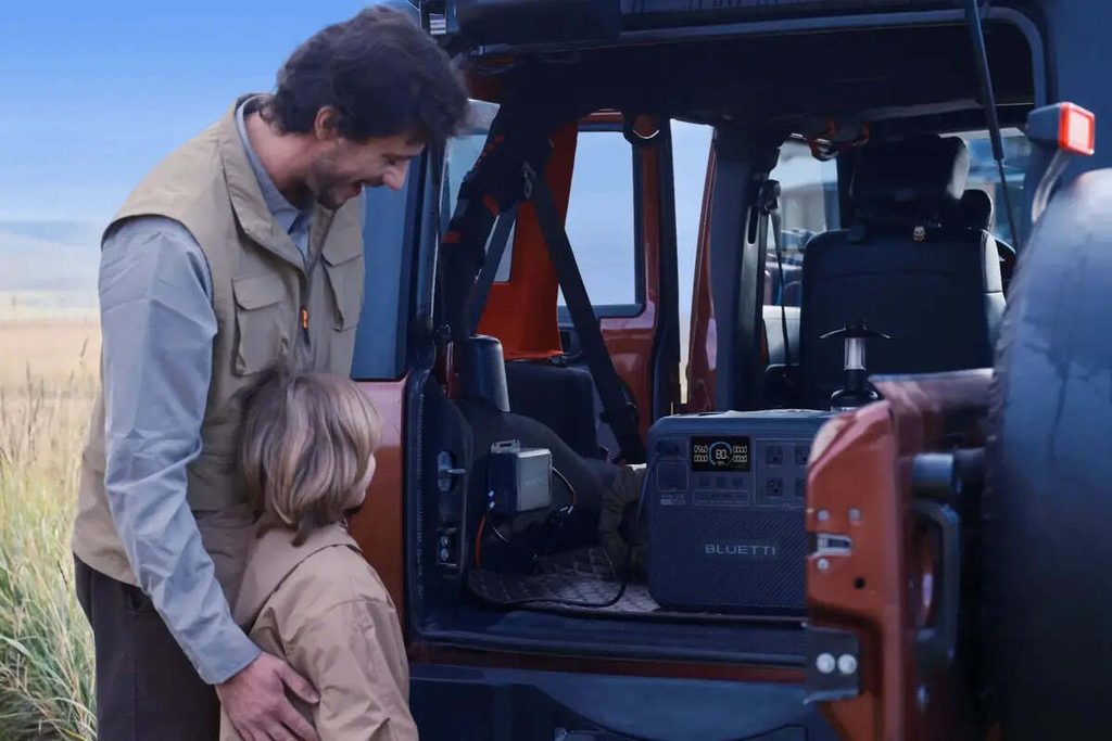 Father and daughter looking at a power station at the back of a car