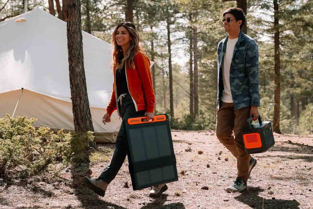 Man and woman carrying power station and a portable solar panel